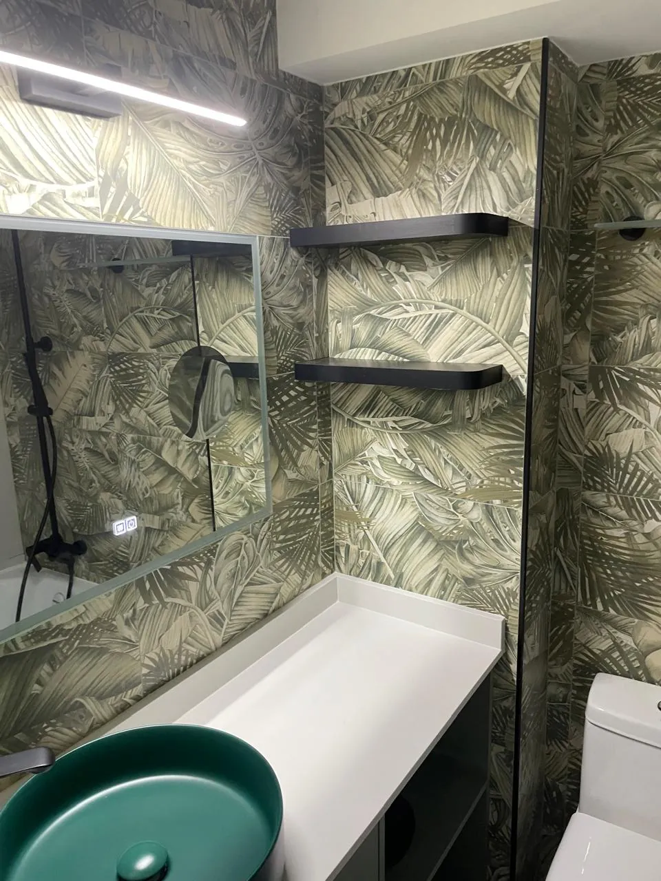 Baño con porcelanato de motivo tropical, tina y grifería negra