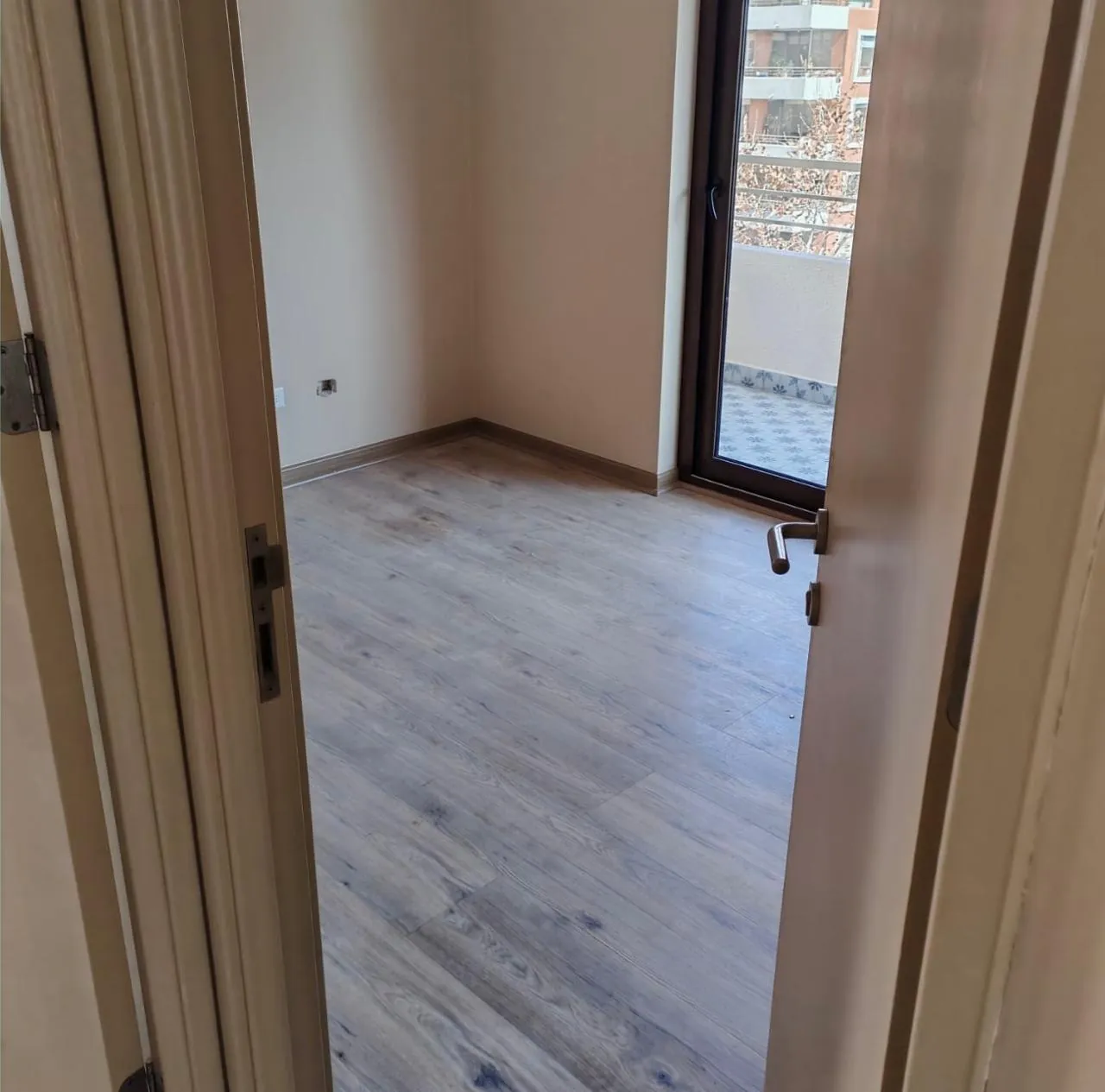 Habitación pequeña con piso flotante claro y guardapolvo instalado
